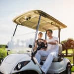 A man and a woman are sitting in a white golf cart
