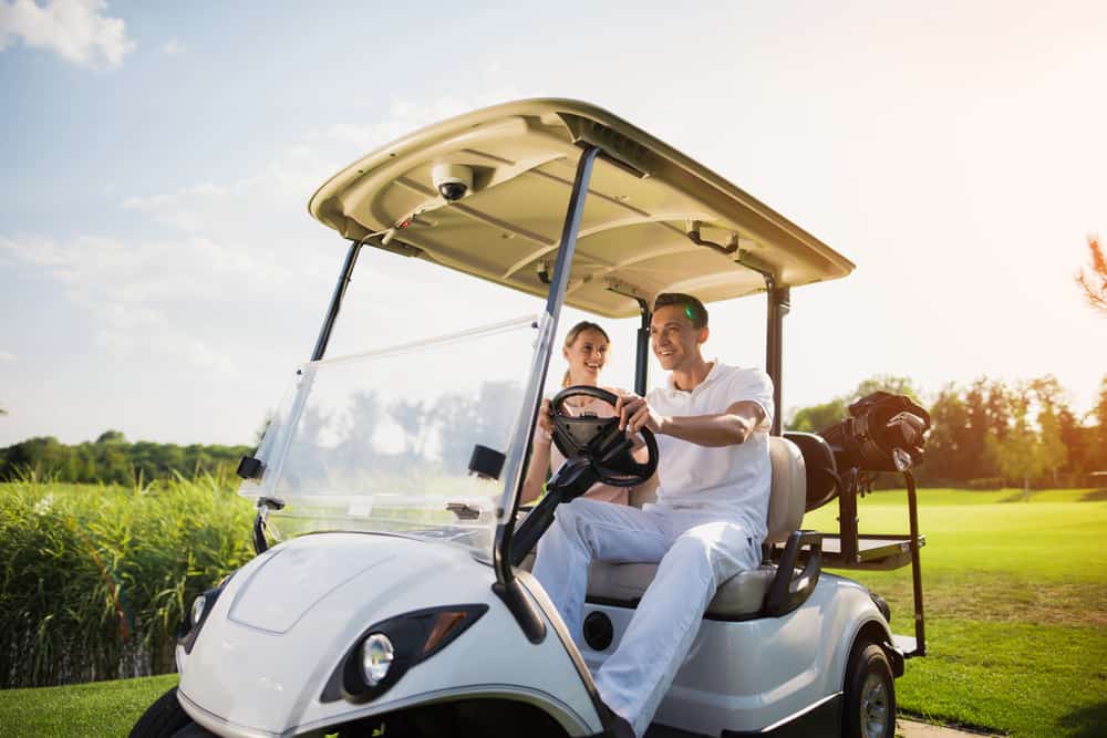 A man and a woman are sitting in a white golf cart