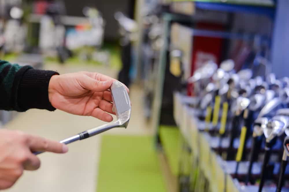 Man holding in hand golf club at a Golf Shop