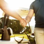 two men shaking hands while standing at the green course