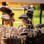 Back view of beautiful couple talking while driving a golf cart, golf clubs in the foreground