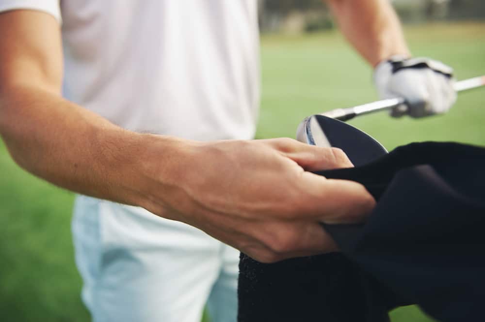 Golfer looking after his clubs by cleaning them after shot