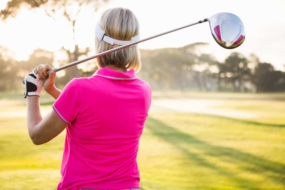 Rear view of sportswoman playing golf on field