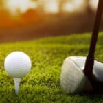 The Golf club and golf ball close up in grass field with sunset