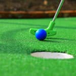A club prepares to hit a ball during a mini golf game