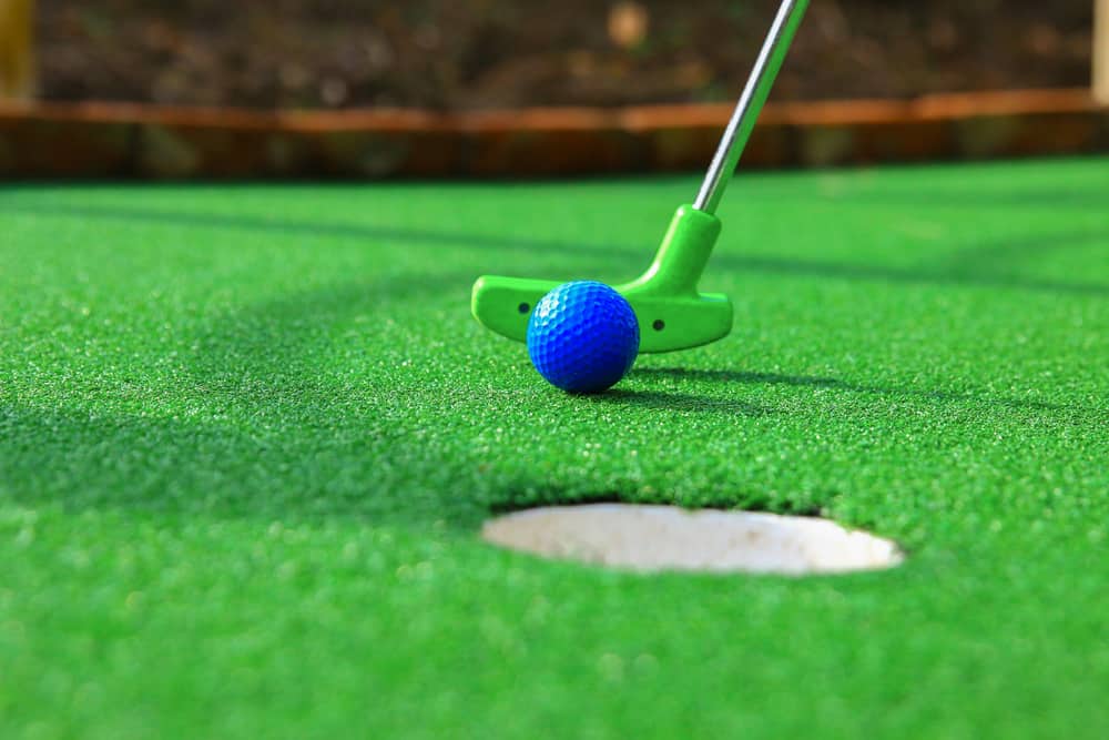 A club prepares to hit a ball during a mini golf game