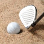 Golf Ball in Trap with Sand Wedge about to strike the Golfball