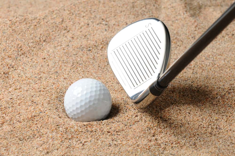 Golf Ball in Trap with Sand Wedge about to strike the Golfball