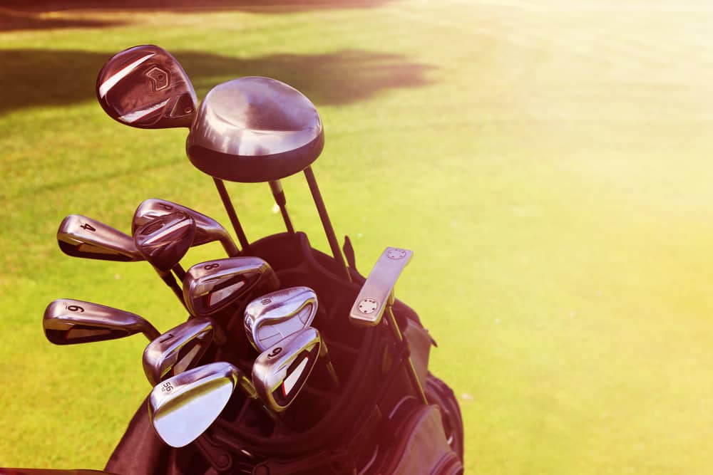 Golf bag with clubs on green field