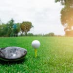 Golf ball and club on green grass