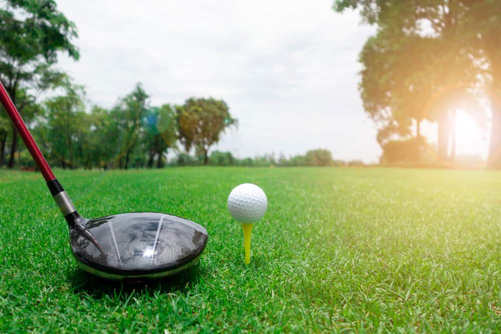 Golf ball and club on green grass