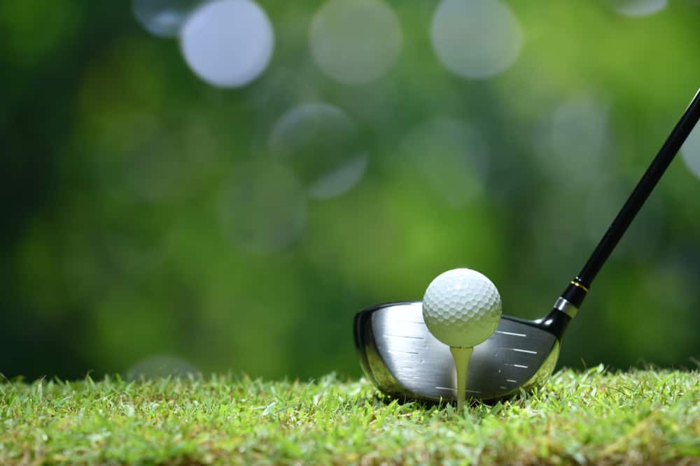 Golf ball on green grass ready to be struck on golf course background