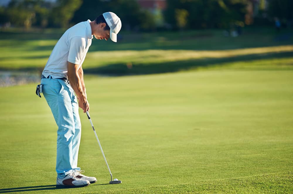 Golf man putting on green for birdie