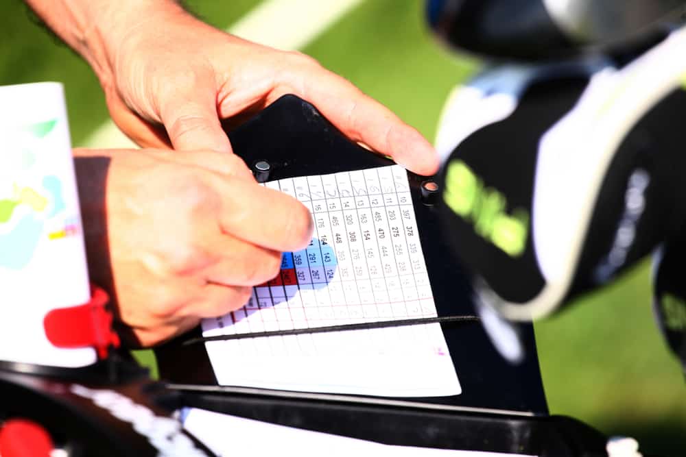 Golfer keeping scores in score sheet with hands