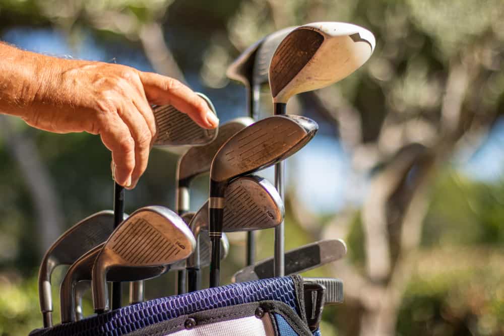 Hand putting a golf iron in a golf bag