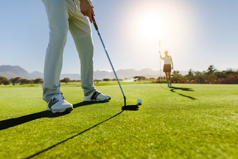 Low angle view of golfer on putting green about to take the shot