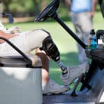 Male Golfer With Artificial Leg Driving Buggy On Golf Course