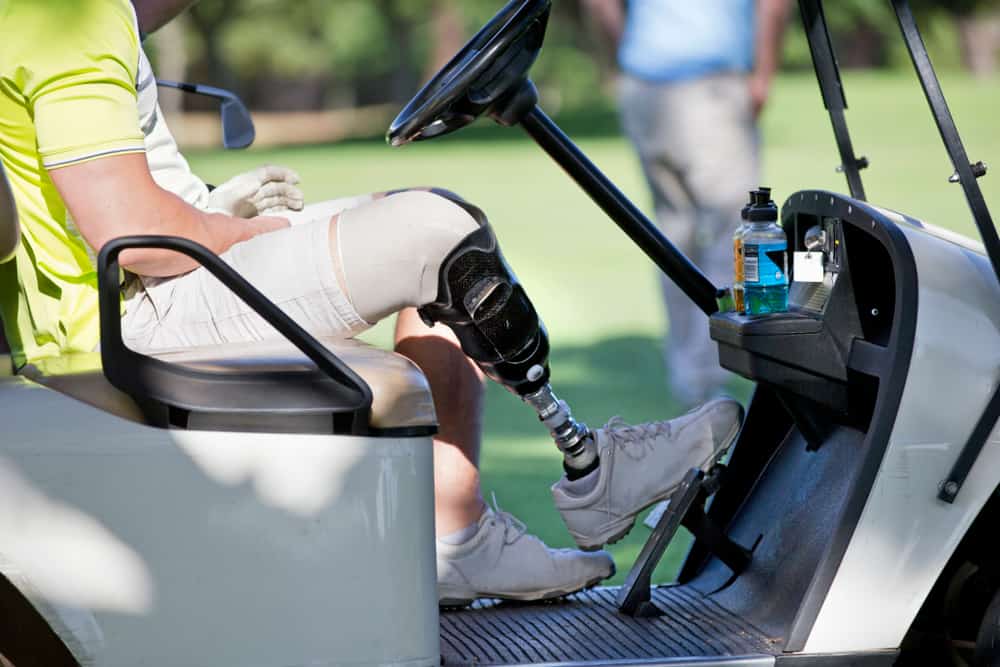 Male Golfer With Artificial Leg Driving Buggy On Golf Course