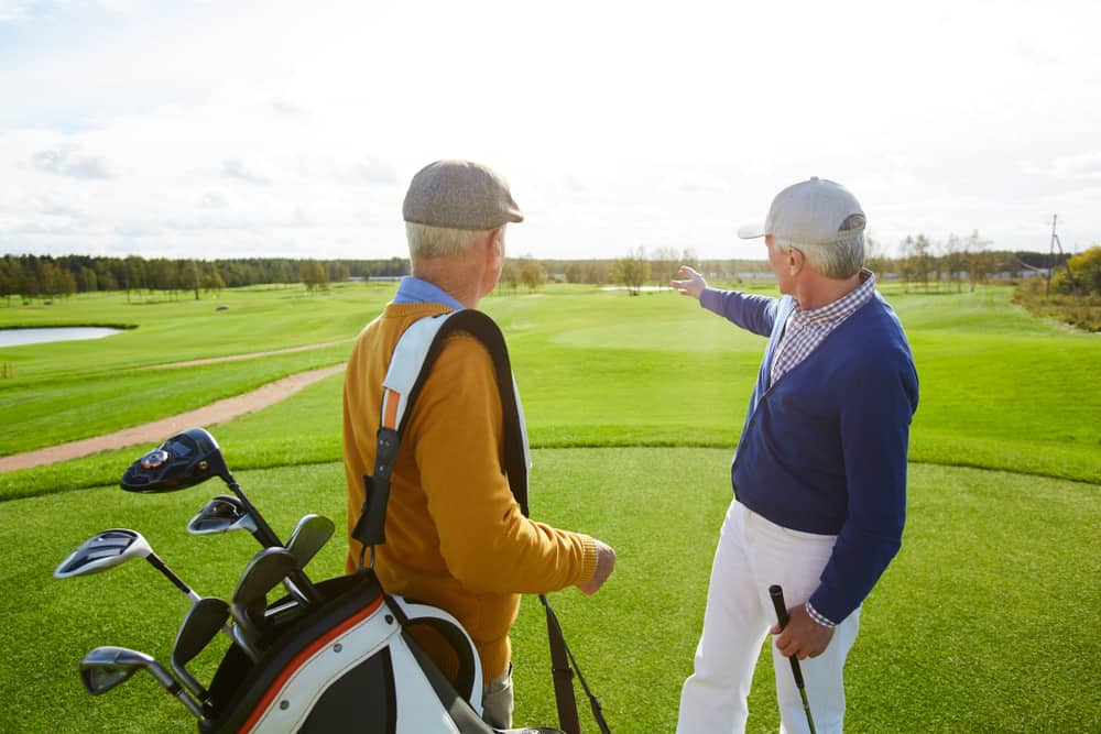 One of senior golf players showing his mate the place where they might play