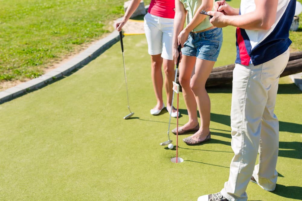 People, man and women, playing miniature golf