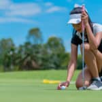 The golfer places the golf ball on the golf green into the hole