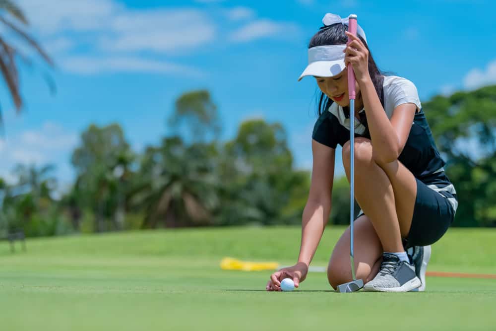 The golfer places the golf ball on the golf green into the hole