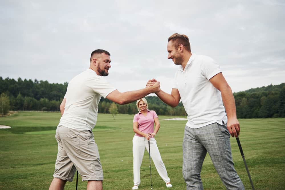 Three players play on the golf course