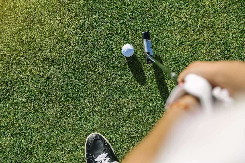 Woman golf player concentrating for putting on green