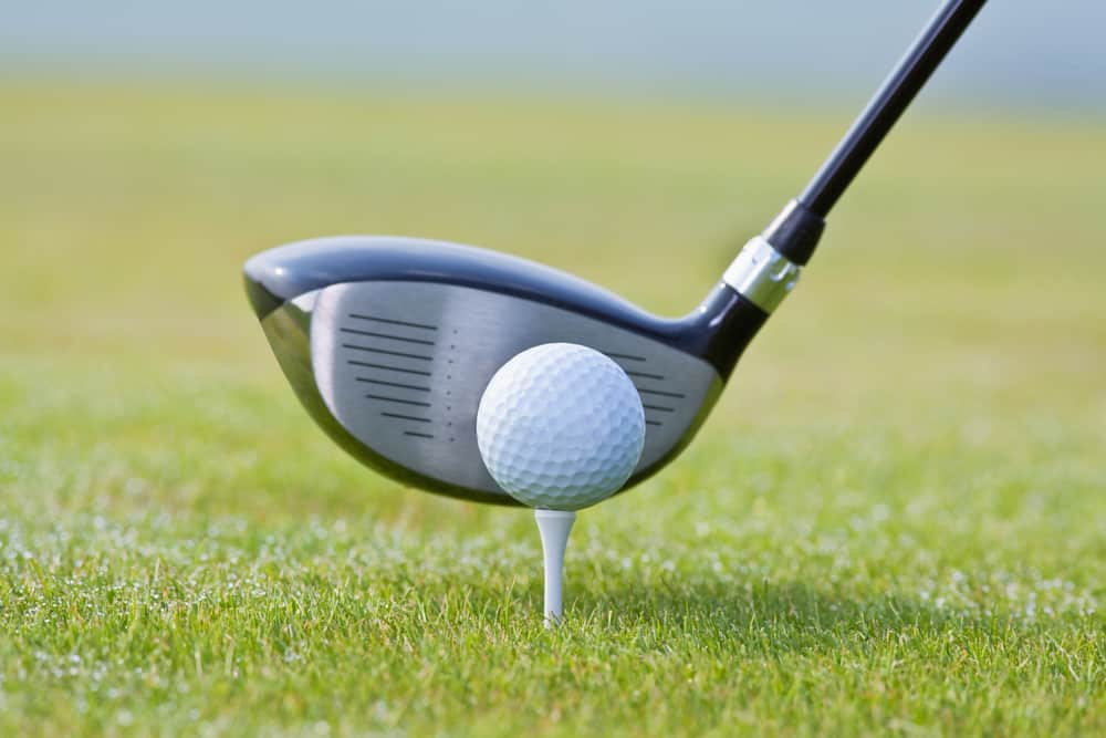 closeup of a golf ball and club on green grass