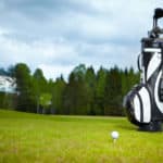 golf bag equipment on green and hole as background