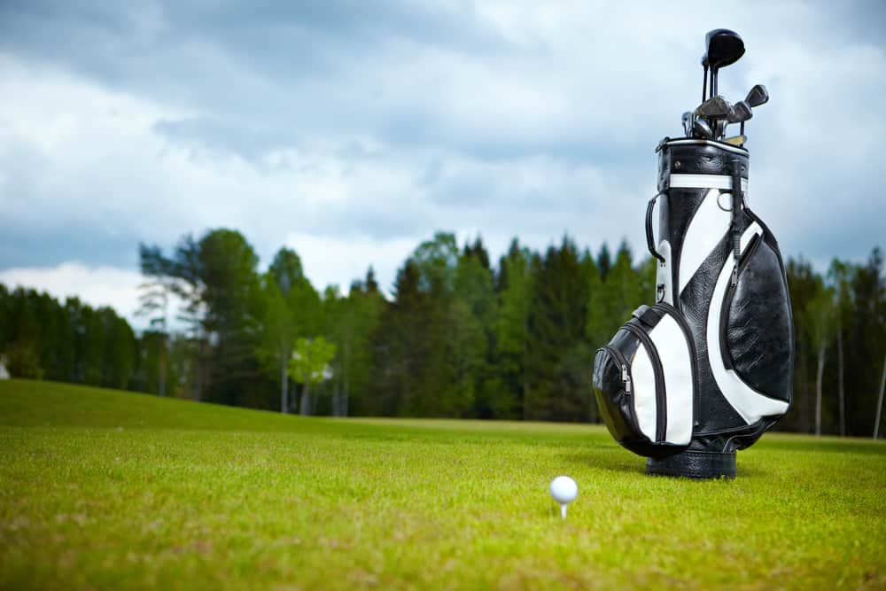 golf bag equipment on green and hole as background