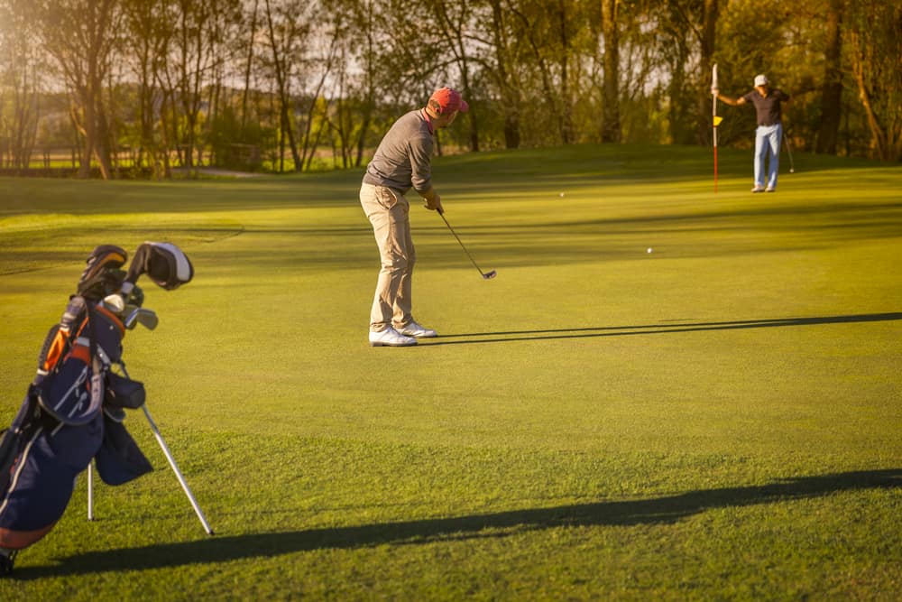 golf player putting on green at twilight