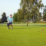 man just putt a ball on a golf course