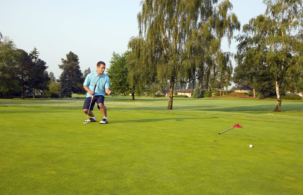 man just putt a ball on a golf course