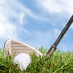 A golder gets ready to hit a golf ball out of the rough during a beautiful, sunny day