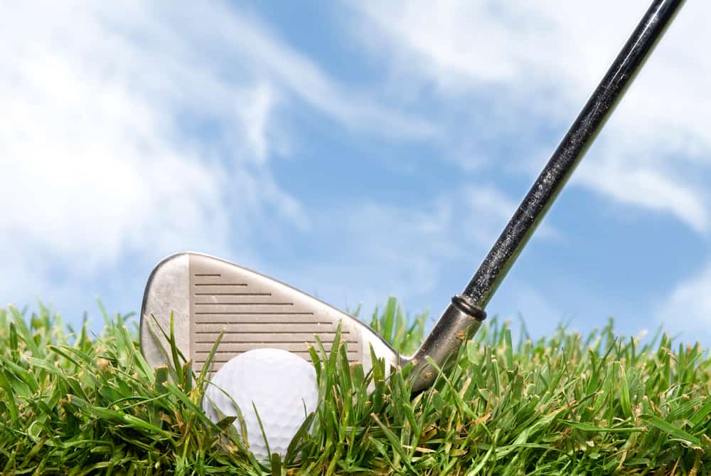 A golder gets ready to hit a golf ball out of the rough during a beautiful, sunny day