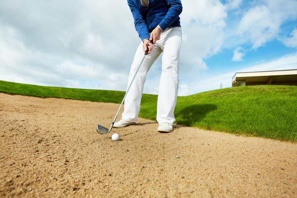 Active man in white pants and blue pullover standing on the ground