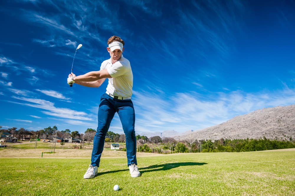 Close up image of a male golfer playing a shot on the fairway on a golf course