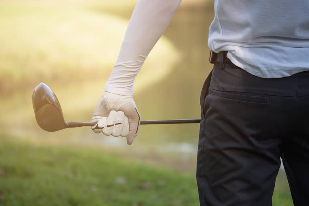 Close up of male golfer's hands holding golf club on green grass