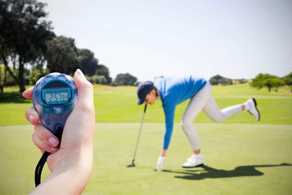 Composite image of a woman holding a chronometer to measure performance against female golfer picking up golf ball