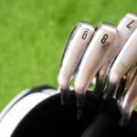 Different golf club in a bag on green grass background