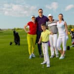 Four adult friends golfers and kid are happy to finish their golf game