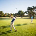 Full length of friends playing golf while standing on field