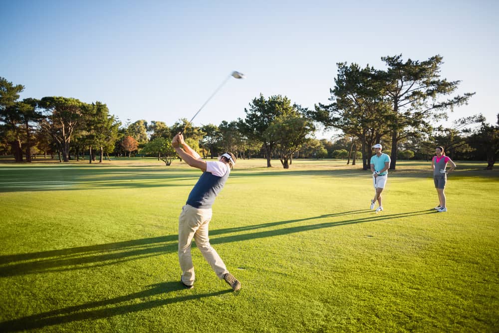 Full length of friends playing golf while standing on field