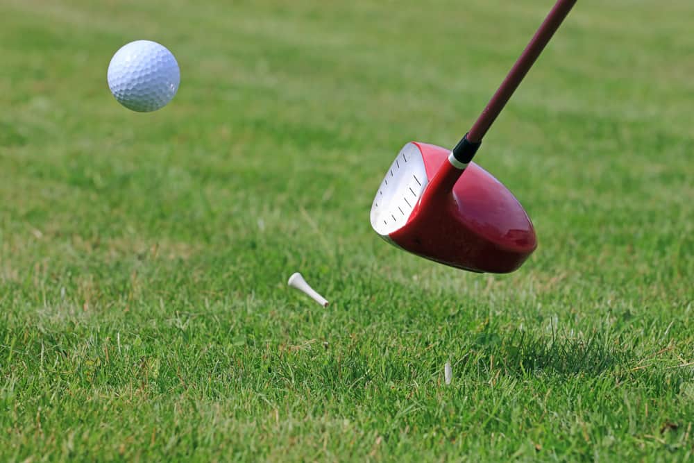 Golf Driver Club Hitting Ball off a Tee on a Golf Course Fairway