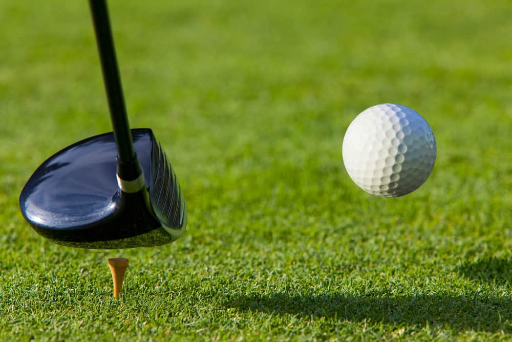 Golf ball hit off the tee with driver on golf course