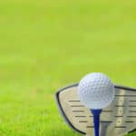 Golf ball on tee in front of driver