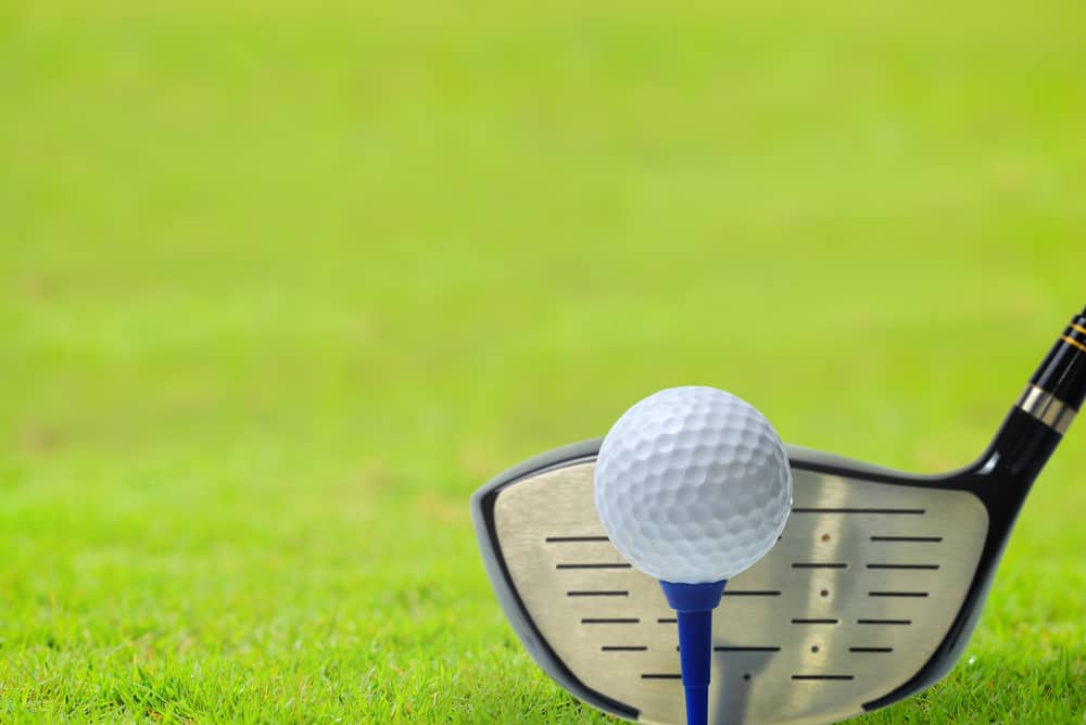 Golf ball on tee in front of driver