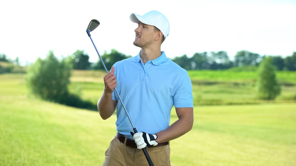 Joyful golf player holding club