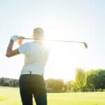 Male golf player teeing off golf ball from tee
